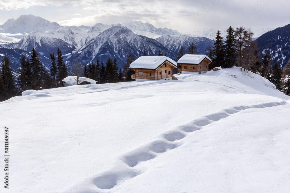 Footprints on snow with Swiss Alps winter landscape and chalets at the background
