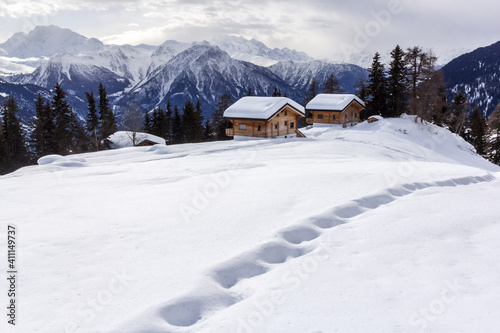 Footprints on snow with Swiss Alps winter landscape and chalets at the background © Yü Lan