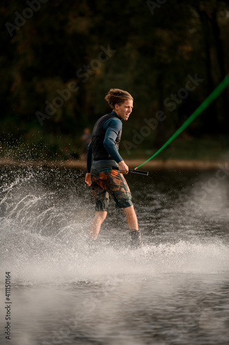 Healthy man riding on wakeboard lifting up a lot of splashes at the river