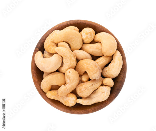 Cashew nuts in wooden bowl, isolated on white background. Roasted cashew nuts. Top view.