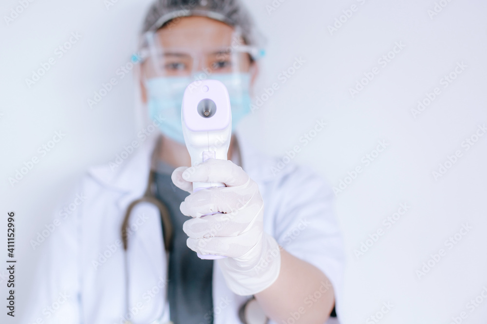 Close-up shot of doctor wearing protective mask ready to use infrared forehead thermometer (thermometer gun) to check body temperature for virus symptoms and epidemic virus outbreak Close-up shot of doctor wearing protective mask ready to use infrared forehead thermometer (thermometer gun) to check body temperature for virus symptoms and epidemic virus outbreak