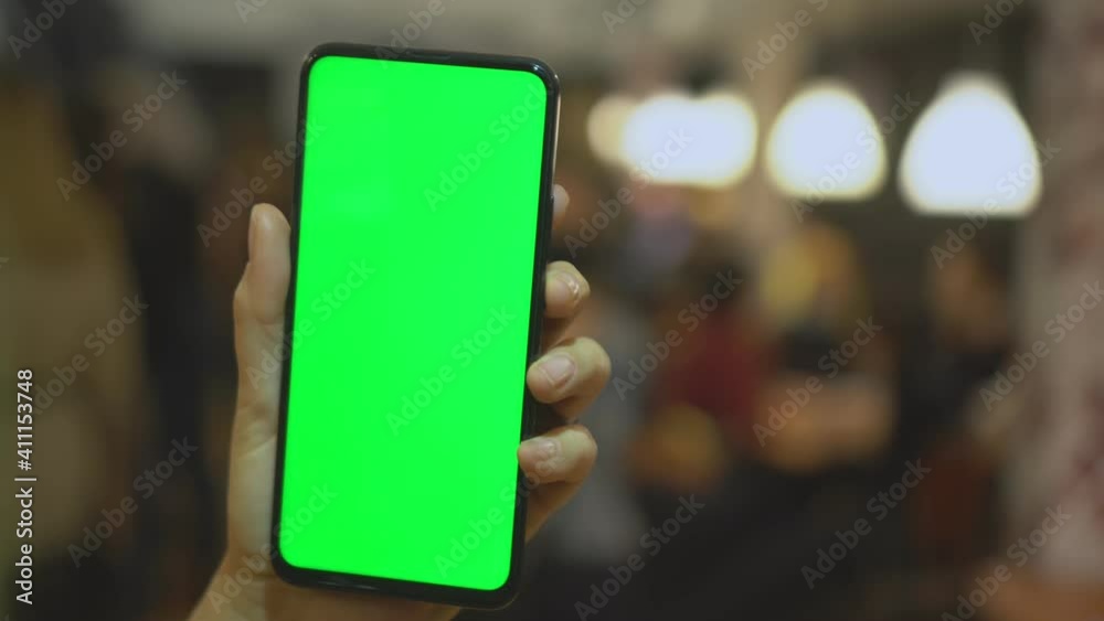 Back view of brunette holding chroma key green screen smartphone watching content. Shopping online. Gadgets and contemporary people concept. Back view of brunette holding chroma key green screen smartphone watching content. Shopping online. Gadgets and contemporary people concept.