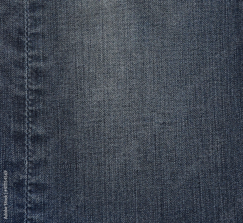 Fade denim jeans with seam at left side. Material, fabric, background textures categories.