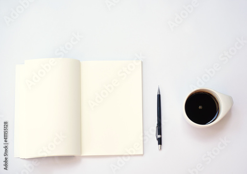 An opened note book,  black pencil and a black coffee are on white background.  Blank pages are good for copy space and texting.  Working, studying and taking a break with simplicity ideas.  