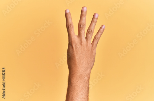Arm and hand of caucasian man over yellow isolated background counting number 4 showing four fingers