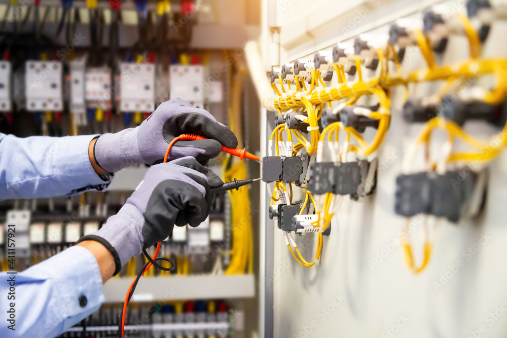 Electrical engineer using digital multi-meter measuring equipment to ...