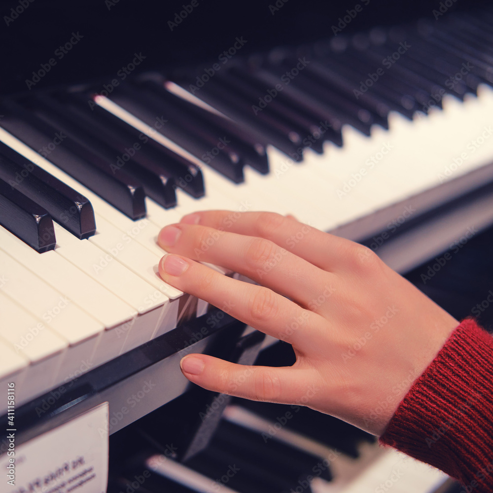 Obraz premium The hand of a child pianist choosing a synthesizer in a musical instrument store. Electronic piano keys, close-up.