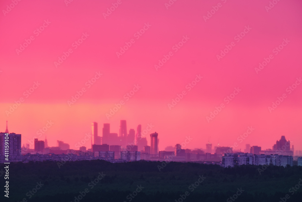 Beautiful pink sunrise behind the houses of Moscow city in fog