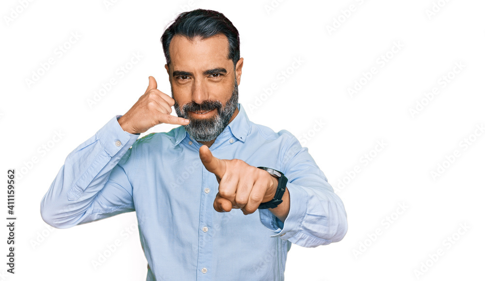 Middle aged man with beard wearing business shirt smiling doing talking on the telephone gesture and pointing to you. call me. Middle aged man with beard wearing business shirt smiling doing talking on the telephone gesture and pointing to you. call me.