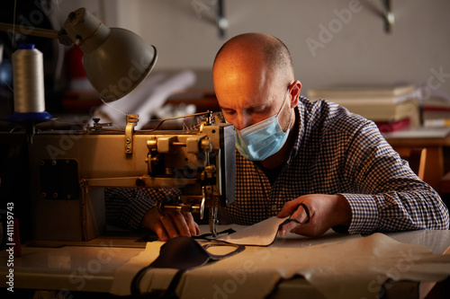 man working with sewing machine doing homemade face mask for preventing and stop corona virus spreading