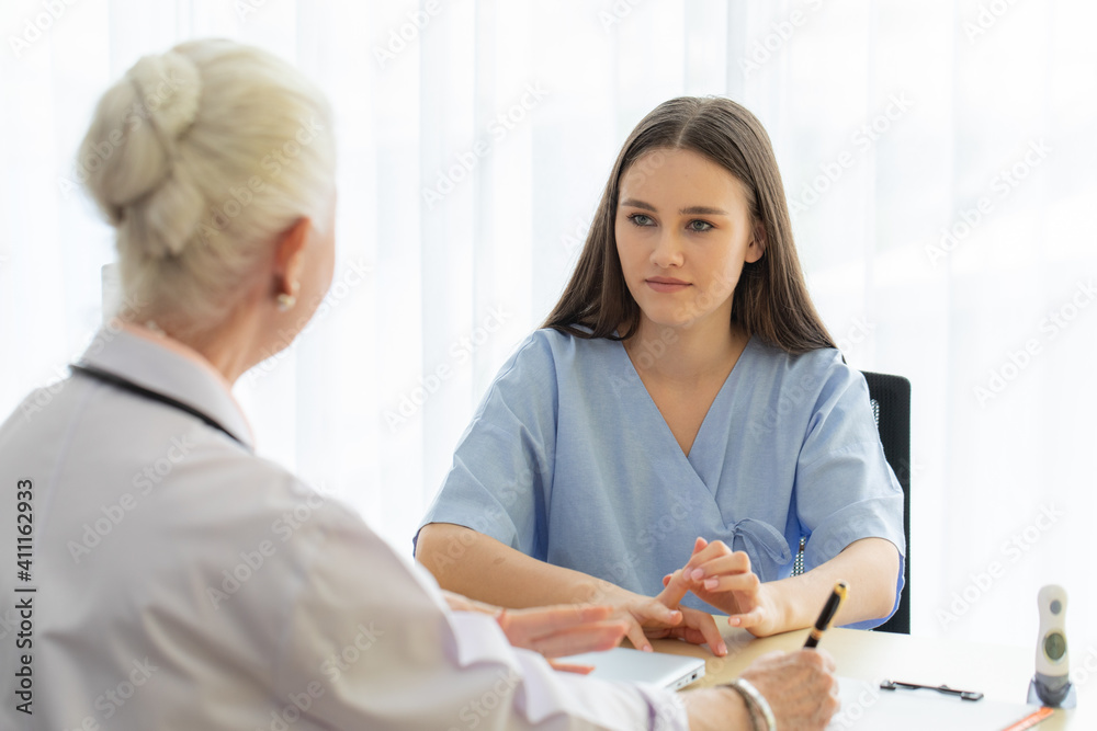 Obraz premium A young and beautiful patient talking to a doctor for history taking for a cure.