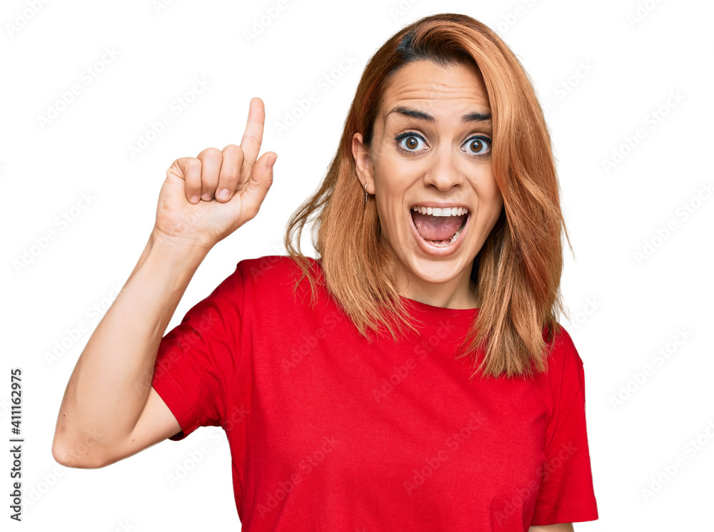 Hispanic young woman wearing casual red t shirt pointing finger up with successful idea. exited and happy. number one. Hispanic young woman wearing casual red t shirt pointing finger up with successful idea. exited and happy. number one.