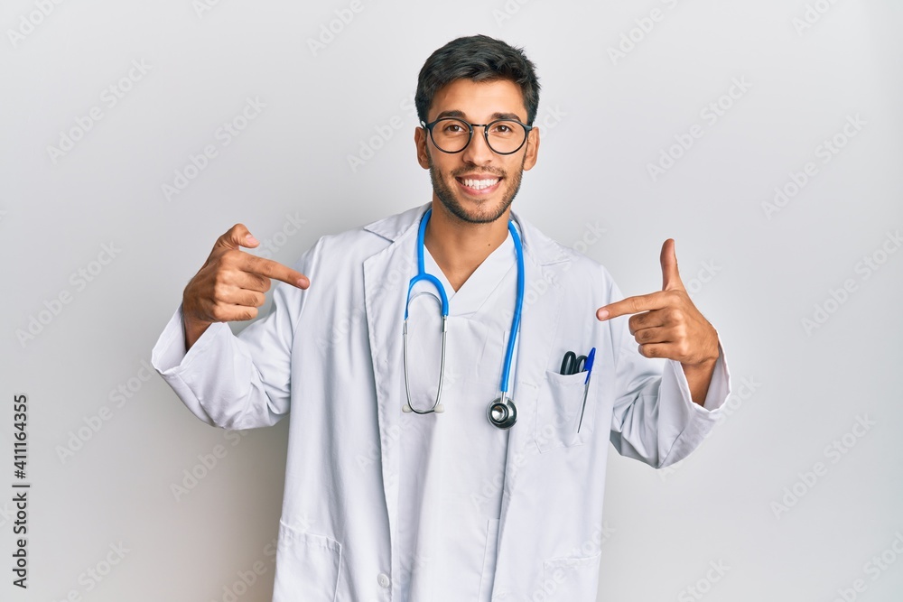 Young handsome man wearing doctor uniform and stethoscope looking confident with smile on face, pointing oneself with fingers proud and happy. Young handsome man wearing doctor uniform and stethoscope looking confident with smile on face, pointing oneself with fingers proud and happy.