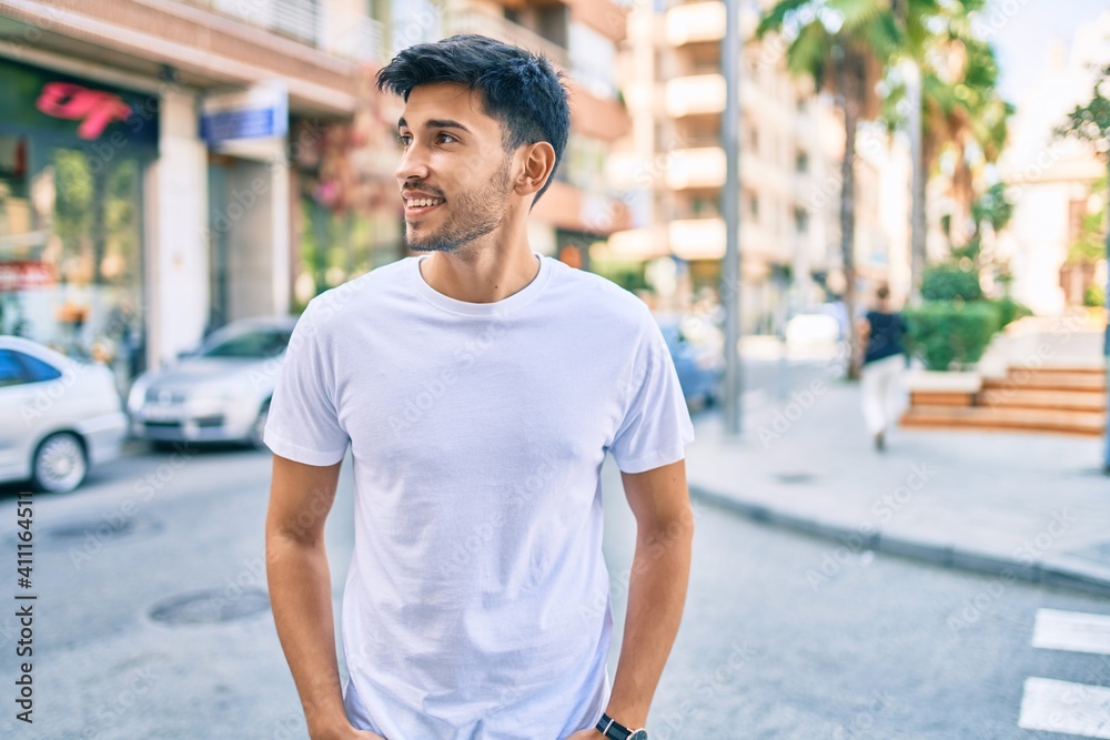 Young latin man smiling happy walking at the city.