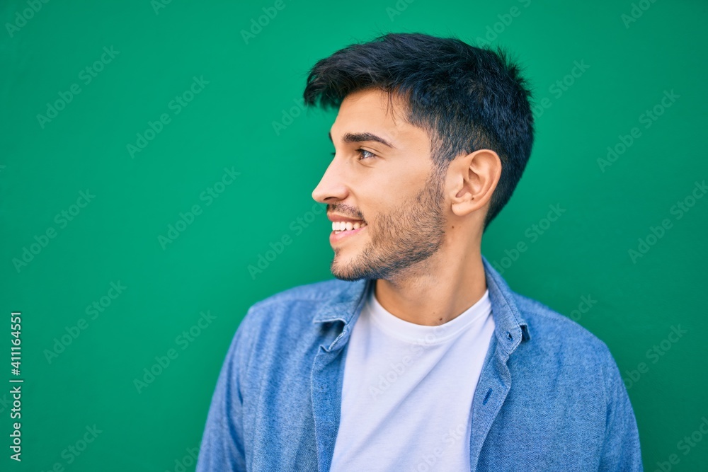 Young latin man smiling happy leaning on the wall at the city. Young latin man smiling happy leaning on the wall at the city.