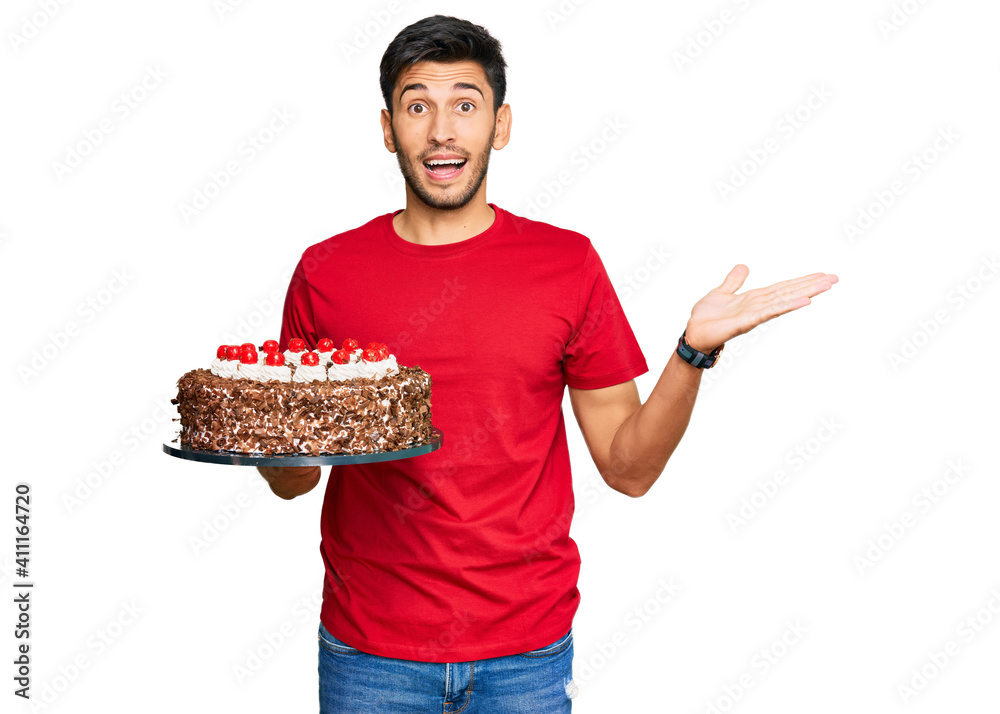 Young handsome man celebrating birthday with cake celebrating victory with happy smile and winner expression with raised hands Young handsome man celebrating birthday with cake celebrating victory with happy smile and winner expression with raised hands