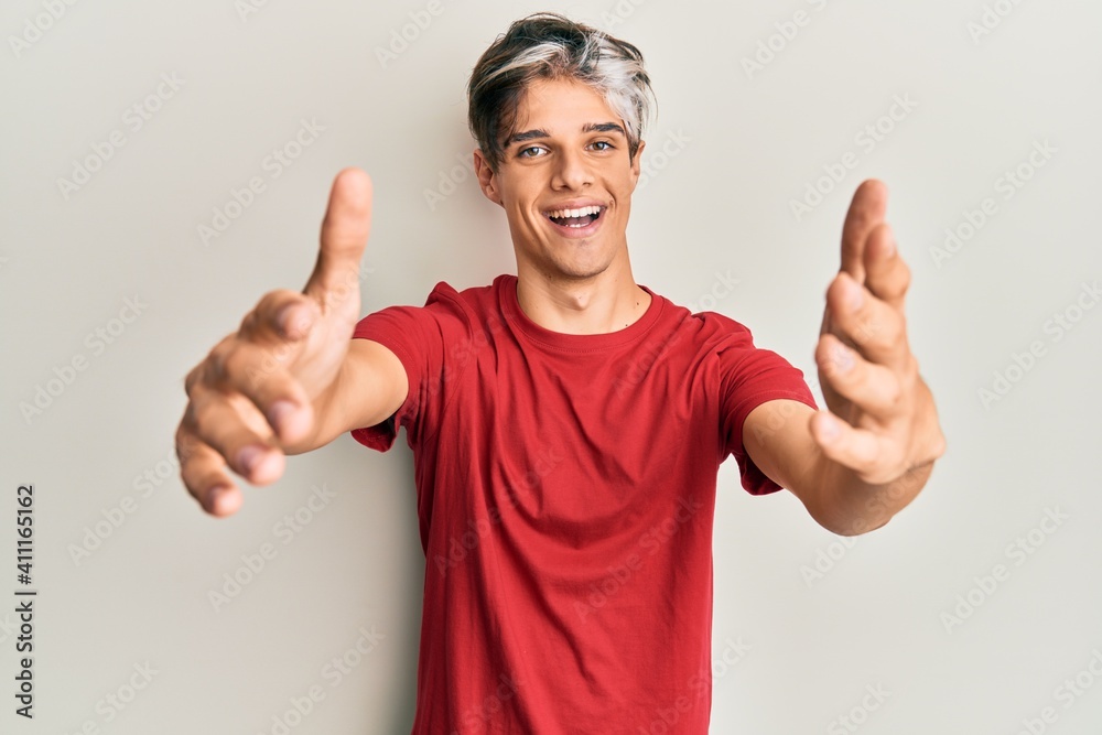Young hispanic man wearing casual clothes looking at the camera smiling with open arms for hug. cheerful expression embracing happiness. Young hispanic man wearing casual clothes looking at the camera smiling with open arms for hug. cheerful expression embracing happiness.