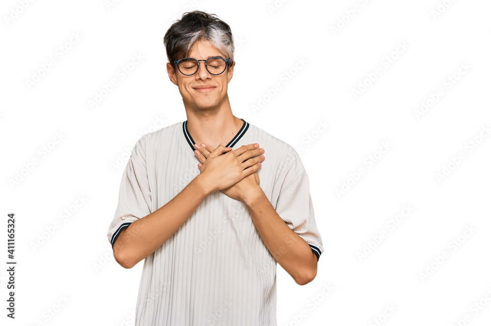 Young hispanic man wearing casual clothes and glasses smiling with hands on chest with closed eyes and grateful gesture on face. health concept. Young hispanic man wearing casual clothes and glasses smiling with hands on chest with closed eyes and grateful gesture on face. health concept.