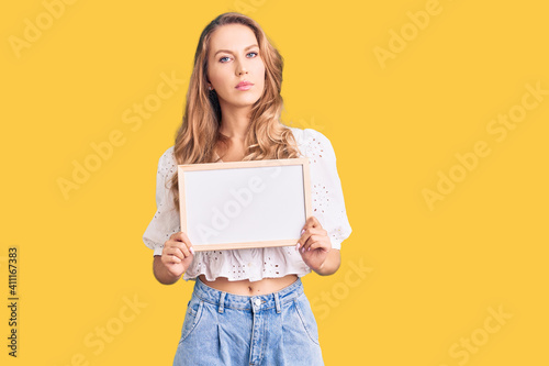 Fotografie Young caucasian woman with blond hair holding blank empty banner thinking attitu