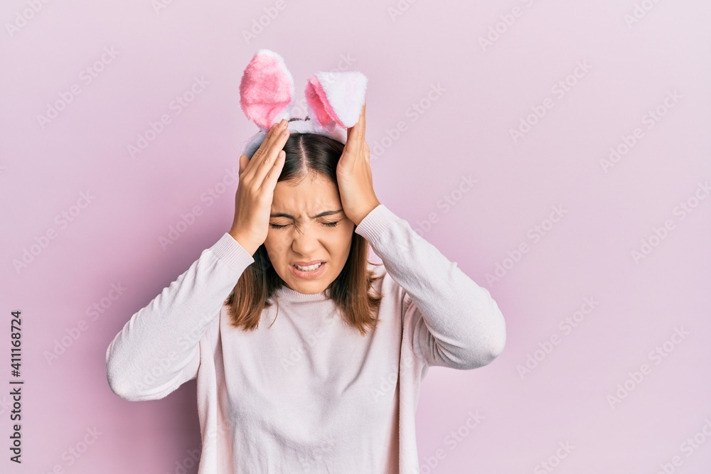 Young beautiful woman wearing cute easter bunny ears suffering from headache desperate and stressed because pain and migraine. hands on head. Young beautiful woman wearing cute easter bunny ears suffering from headache desperate and stressed because pain and migraine. hands on head.