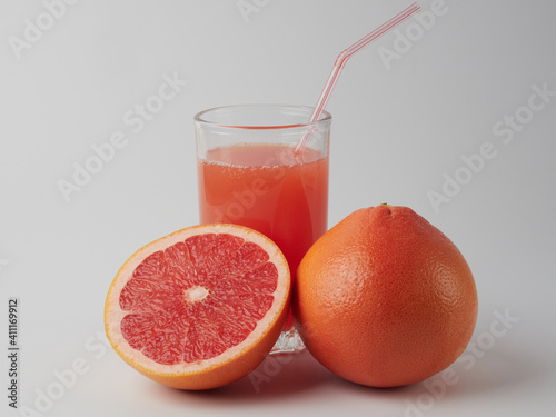 Fresh grapefruits and a glass of grapefruit juice on a white wooden background with a copy space. Close-up.