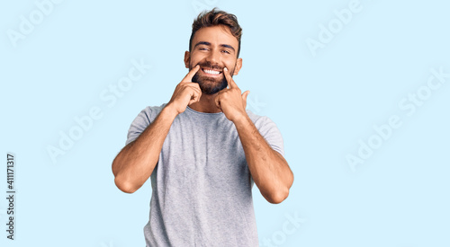 Fotografi Young hispanic man wearing casual clothes smiling with open mouth, fingers point