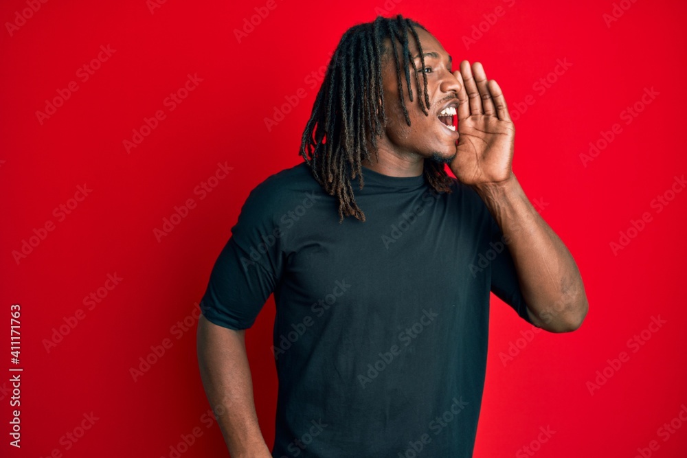 African american man with braids wearing casual clothes shouting and screaming loud to side with hand on mouth. communication concept.