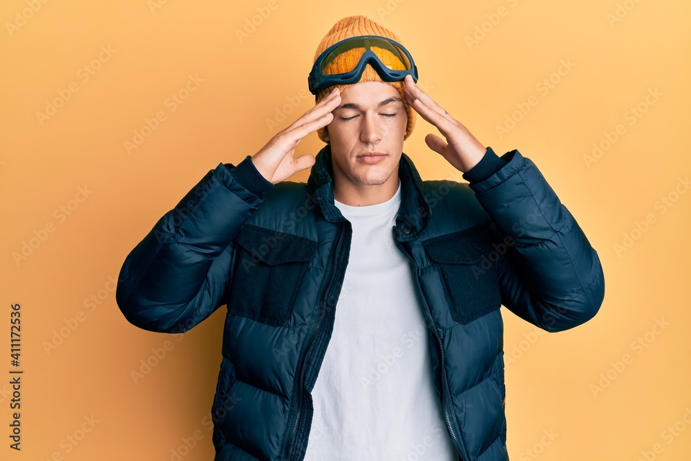 Handsome caucasian man wearing snow wear and sky glasses with hand on head, headache because stress. suffering migraine. Handsome caucasian man wearing snow wear and sky glasses with hand on head, headache because stress. suffering migraine.