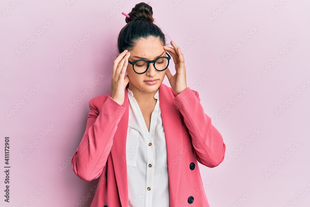Beautiful middle eastern woman wearing business jacket and glasses with hand on head, headache because stress. suffering migraine. Beautiful middle eastern woman wearing business jacket and glasses with hand on head, headache because stress. suffering migraine.
