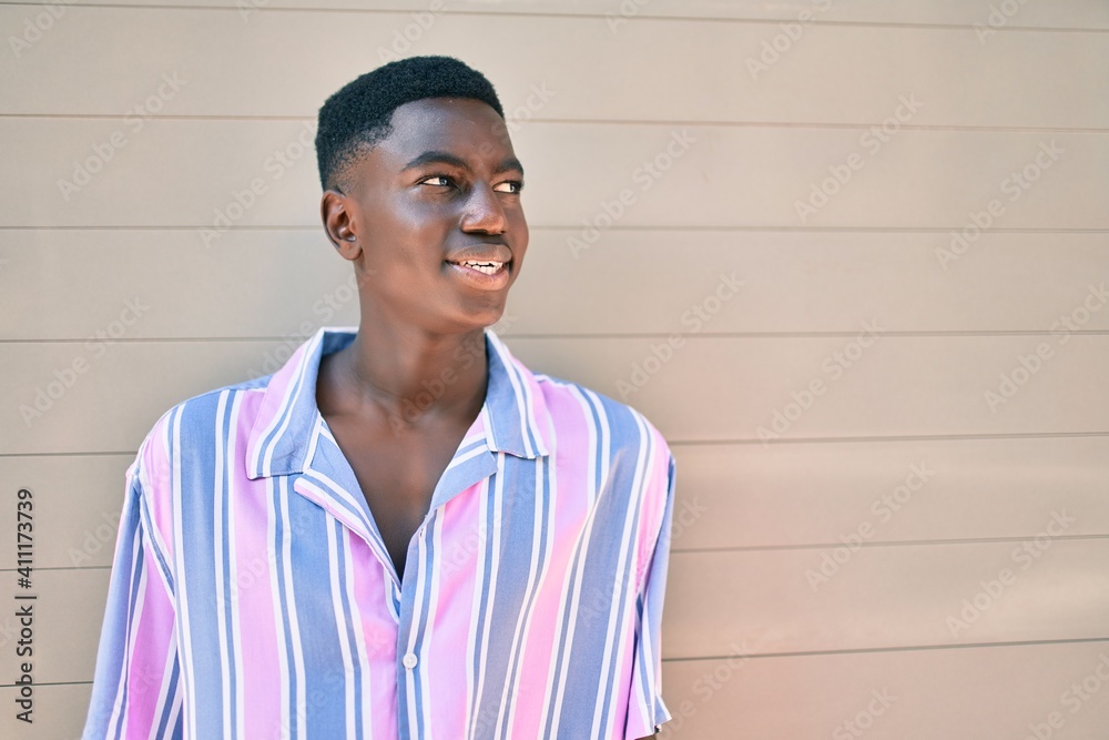 Young african american man smiling happy leaning on the wall at street of city. Young african american man smiling happy leaning on the wall at street of city.