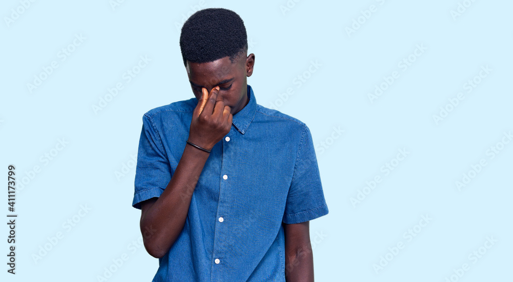Fototapeta premium Young african american man wearing casual clothes tired rubbing nose and eyes feeling fatigue and headache. stress and frustration concept.