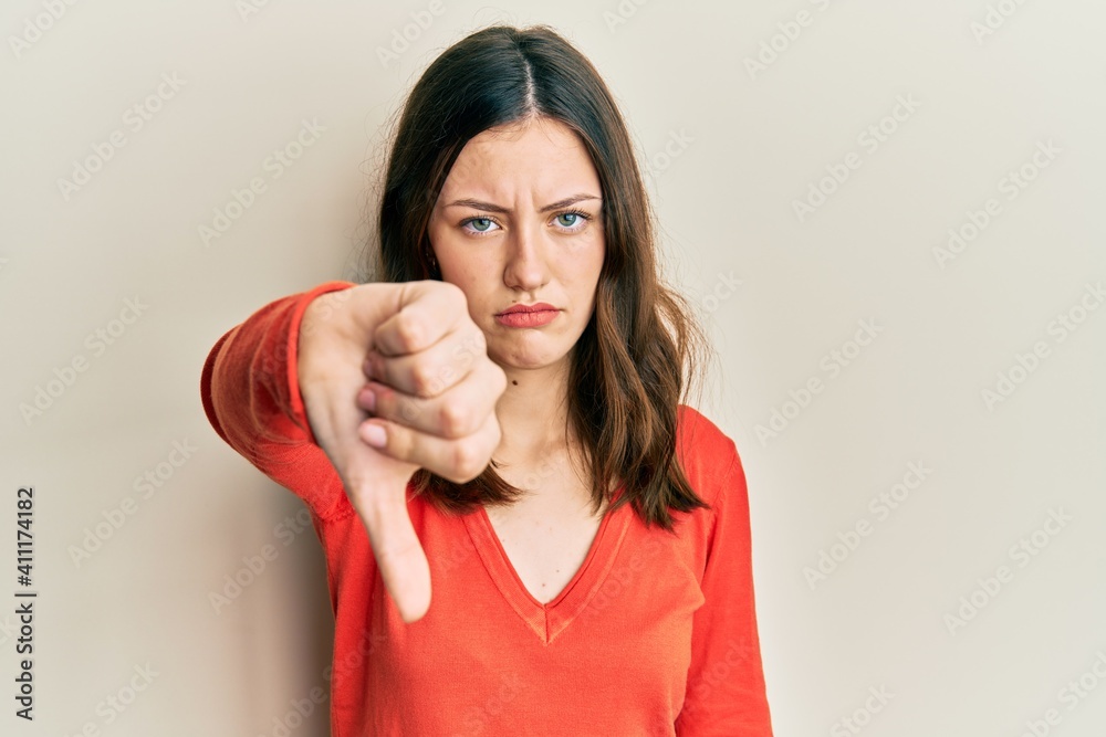 Young brunette woman wearing casual clothes looking unhappy and angry showing rejection and negative with thumbs down gesture. bad expression. Young brunette woman wearing casual clothes looking unhappy and angry showing rejection and negative with thumbs down gesture. bad expression.