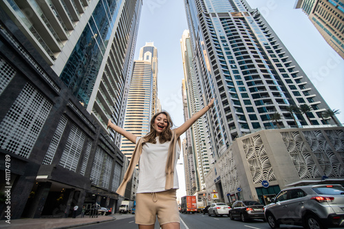 Young woman standing in awe underneath skyscrapers and office buildings in an urban metropolis. Low angle view.