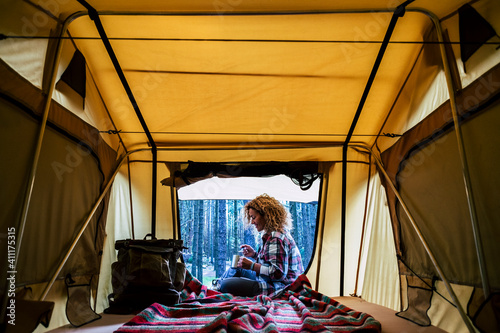 Travel woman sitting in the auto tent and enjoying outdoors from the window with amazing landscape. Best wake up during adventure trip with feeling. Concept of nature and having freedom in holiday