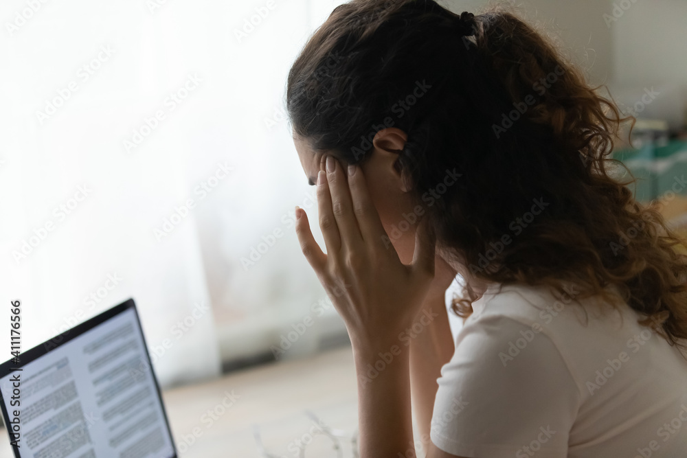 Lack of ideas. Hard working female sitting by laptop pc rubbing temples feeling difficult to concentrate reading text on screen. Tired young woman overworked by computer suffer of headache migraine Lack of ideas. Hard working female sitting by laptop pc rubbing temples feeling difficult to concentrate reading text on screen. Tired young woman overworked by computer suffer of headache migraine