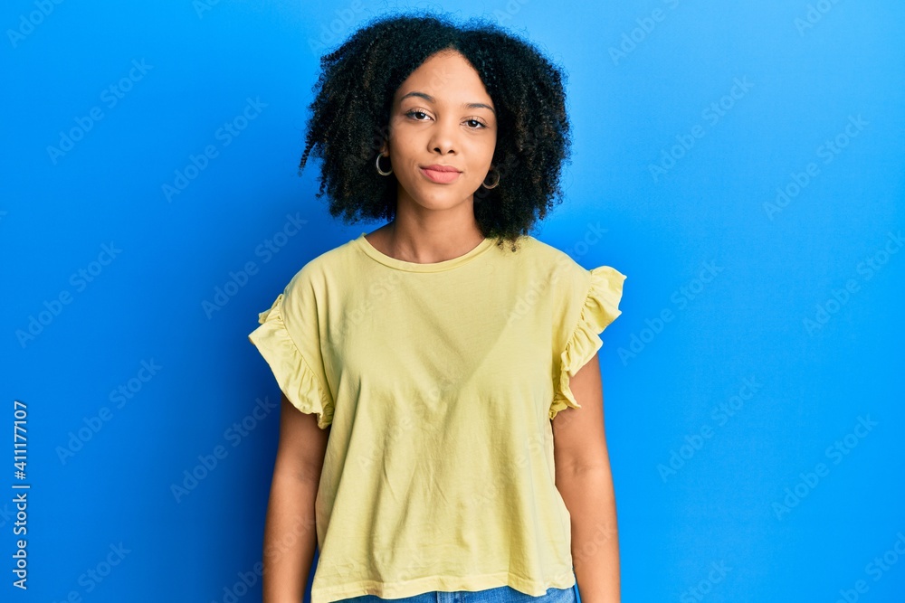 Young african american girl wearing casual clothes relaxed with serious expression on face. simple and natural looking at the camera. Young african american girl wearing casual clothes relaxed with serious expression on face. simple and natural looking at the camera.