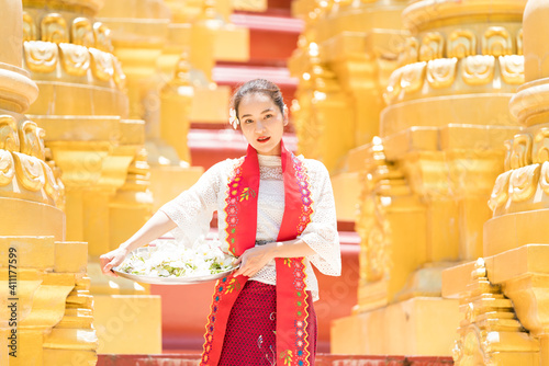 Young woman with traditional burmese holding Flower tray on the hand at beautiful golden pagoda in Myanmar. photo