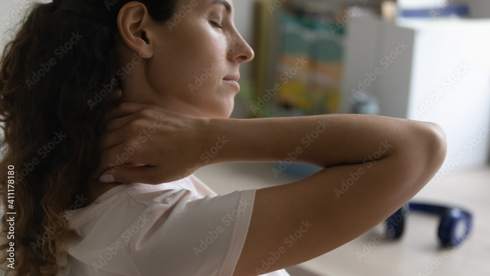 Close up of millennial woman tired at sedentary work massaging neck relieving pain. Attractive young female feeling strained back muscles tension stretching relaxing at home workplace with closed eyes Close up of millennial woman tired at sedentary work massaging neck relieving pain. Attractive young female feeling strained back muscles tension stretching relaxing at home workplace with closed eyes