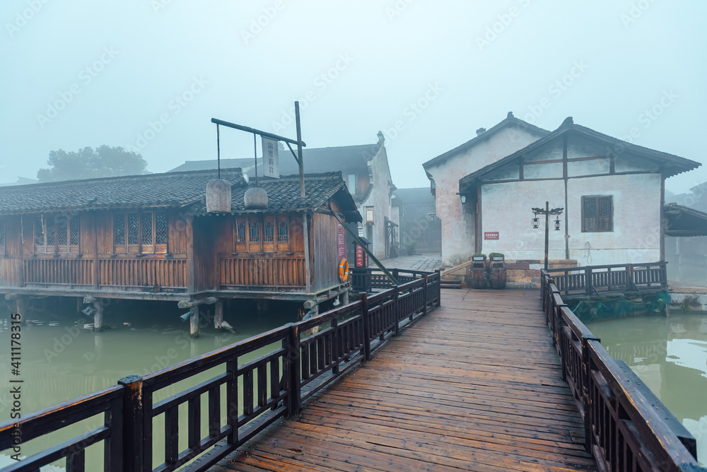 WUZHEN,CHINA-MARCH 6,2012: Ancient bridge over the canal . Morning fog over the city.