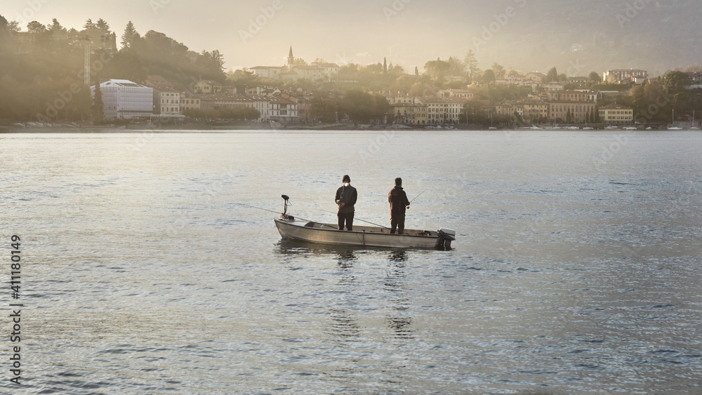 Naklejka premium Fishermen on their boat on Lake Como near Lecco. Malgrate on background