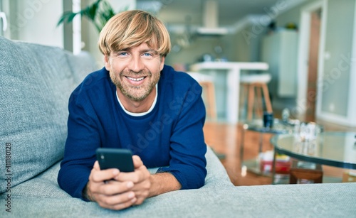 Wallpaper Mural Middle age handsome caucasian man relaxing on the sofa with smartphone Torontodigital.ca