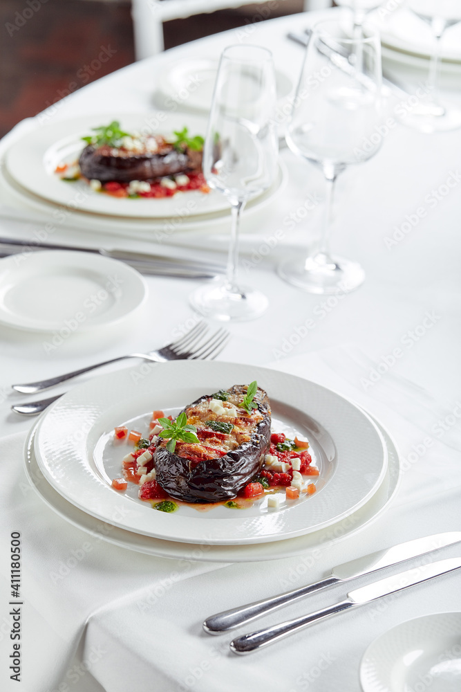 Half baked eggplants with meat, cheese and tomatoes on white background. Banquet festive dishes. Gourmet restaurant menu. White background. Half baked eggplants with meat, cheese and tomatoes on white background. Banquet festive dishes. Gourmet restaurant menu. White background.