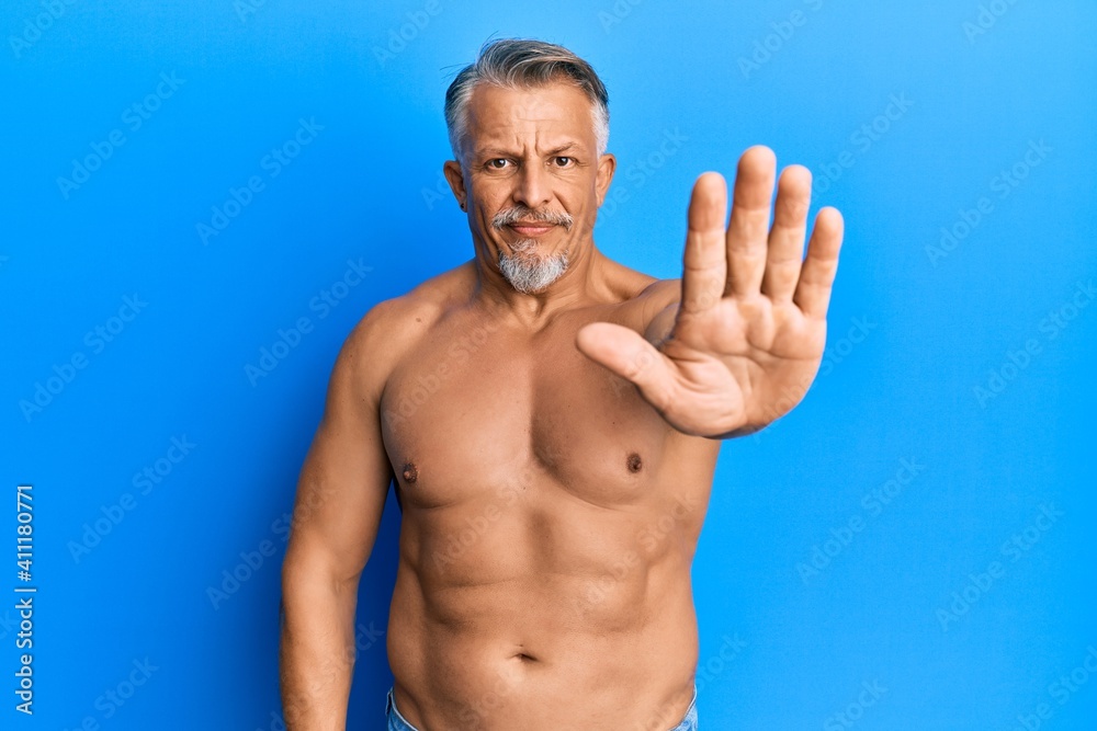 Fototapeta premium Middle age grey-haired man standing shirtless doing stop sing with palm of the hand. warning expression with negative and serious gesture on the face.