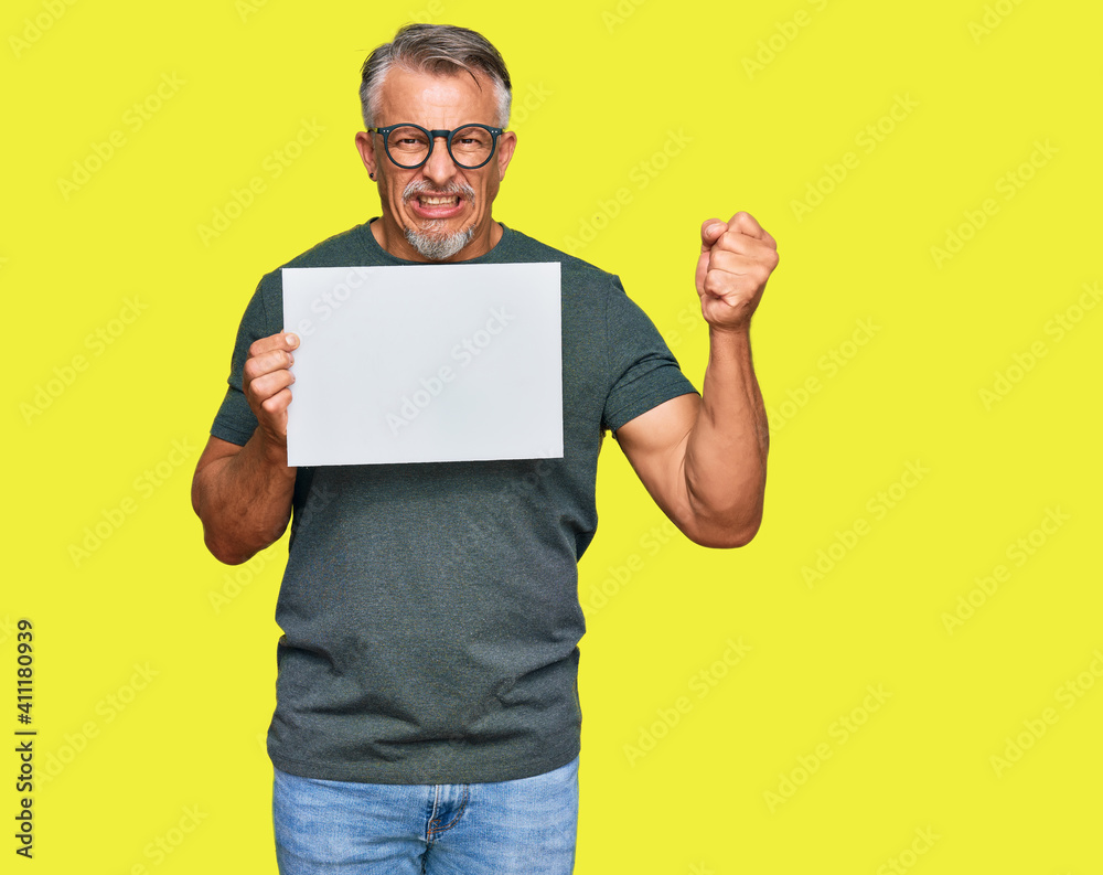 Middle age grey-haired man holding blank empty banner annoyed and frustrated shouting with anger, yelling crazy with anger and hand raised Middle age grey-haired man holding blank empty banner annoyed and frustrated shouting with anger, yelling crazy with anger and hand raised