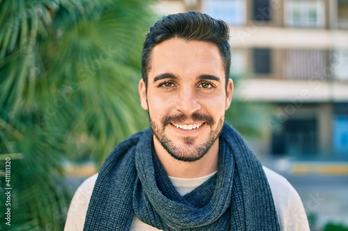Young hispanic man smiling happy wearing scarf walking at the park.