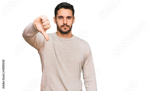 Young hispanic man wearing casual clothes looking unhappy and angry showing rejection and negative with thumbs down gesture. bad expression. © Krakenimages.com