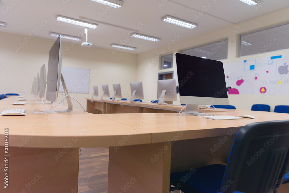 Modern office with computers on desks. Empty computer room in college. Interior of classroom with computers. Concept of corporate working space. Modern office with computers on desks. Empty computer room in college. Interior of classroom with computers. Concept of corporate working space.