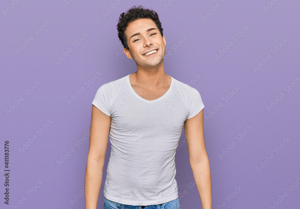 Young handsome man wearing casual white t shirt looking positive and happy standing and smiling with a confident smile showing teeth