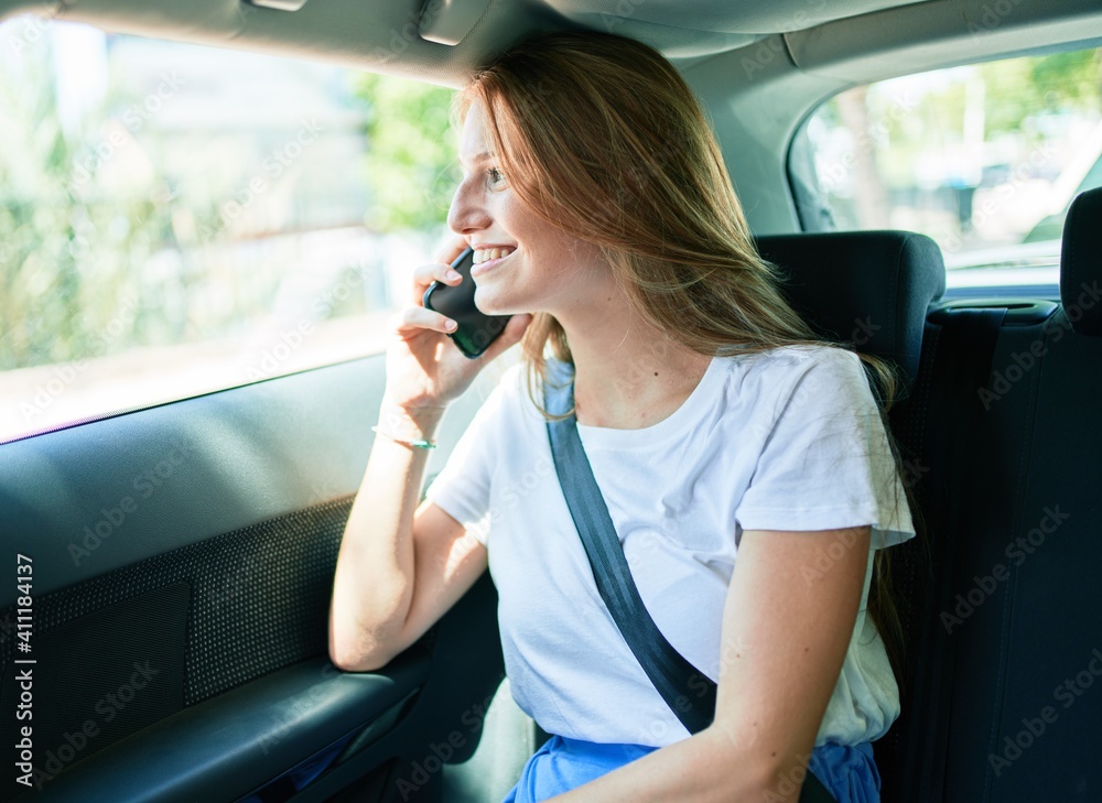 Young beautiful blonde woman smiling happy sitting at the car talking on the smartphone. Young beautiful blonde woman smiling happy sitting at the car talking on the smartphone.