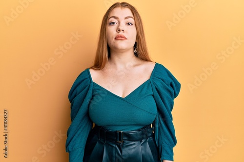 Young beautiful redhead woman wearing elegant and sexy look relaxed with serious expression on face. simple and natural looking at the camera.